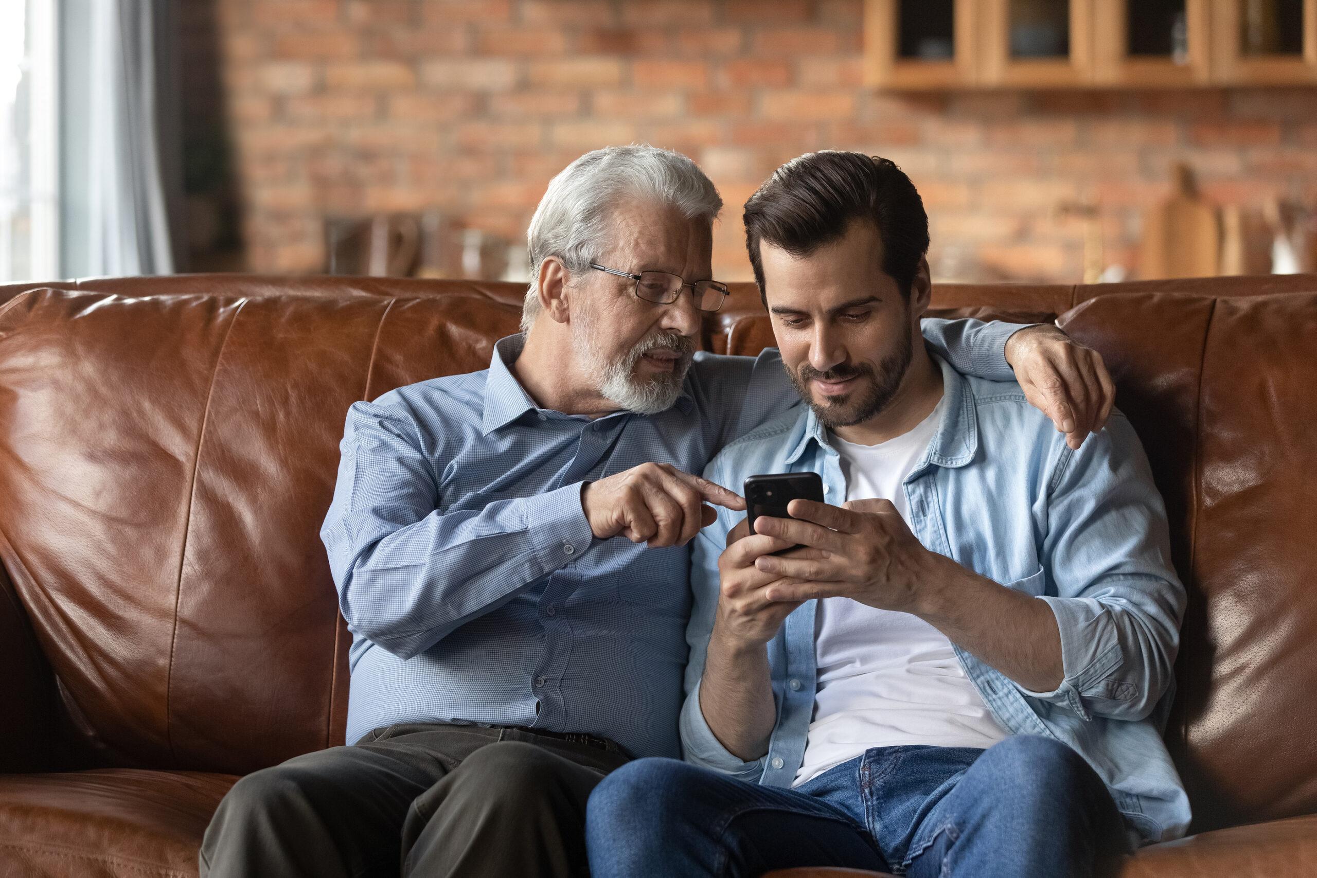 Elderly Father And Adult Son Use Cellphone At Home